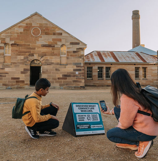 Mother and son scanning a Talking Object Tour sign with their phone in the Convict Precinct on Cockatoo Island.